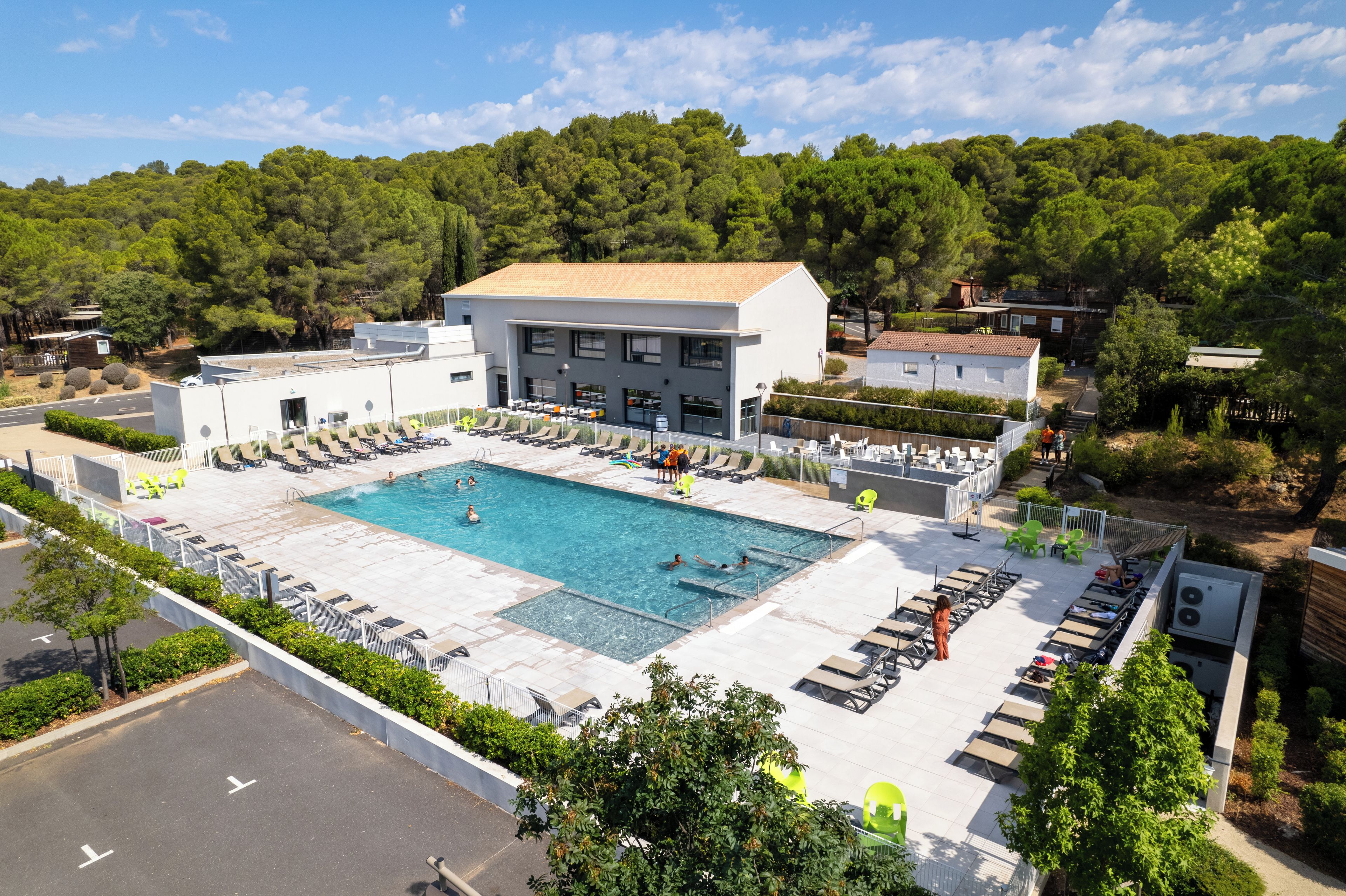Une piscine avec des chaises longues et un bâtiment doté d’un toit plat.
