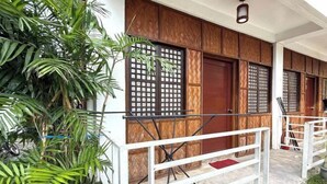 A traditional wooden building with a balcony, surrounded by lush greenery. - Camp Saint John Hotel La Union (San Juan)