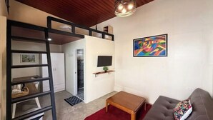 A compact living space with a bunk bed, a television, a red rug, and a sofa. - Camp Saint John Hotel La Union (San Juan)