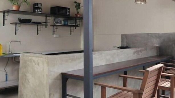A modern kitchen with built-in appliances, wooden chairs, and pendant lighting. - Camp Saint John Hotel La Union (San Juan)