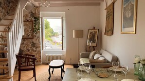 Un coin repas avec une table dressée pour quatre personnes, un canapé et un escalier agrémenté d’une plante.