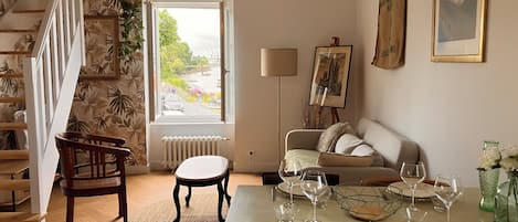 A dining area with a table set for four, a sofa, and a staircase with a plant.