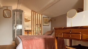 Une chambre à coucher avec un lit, des meubles en bois, un miroir et une salle de bain avec une douche.