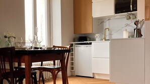 Une cuisine moderne avec des meubles blancs, un four à micro-ondes encastré et une hotte de cuisinière en acier inoxydable.