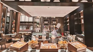 Een modern restaurant met een kok die gerechten bereidt, een buffet met diverse gerechten en een stijlvol interieur.