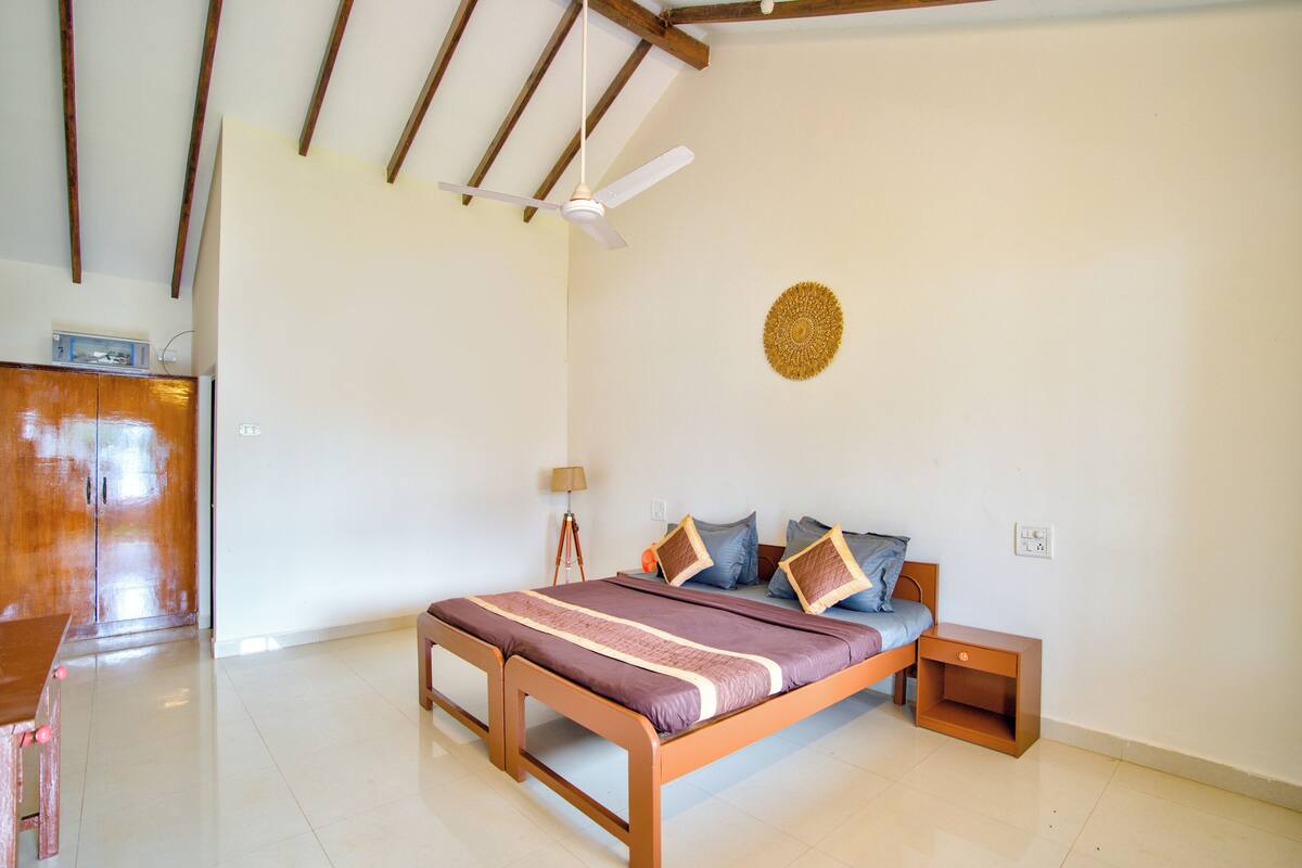 Ein Schlafzimmer mit einem hölzernen Bett, einem kleinen Nachttisch, einem Deckenventilator und einem dekorativen Wandbild.