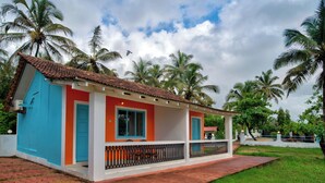 Ein zweistöckiges Haus mit rotem Dach, blauen und orangefarbenen Wänden und einem Balkon mit schwarzer Geländer.