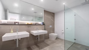 A modern bathroom with two sinks, a glass shower enclosure, and a toilet. - Oceans Edge #25 | Top Floor,1 Min to Terrigal Beach| Accom Holidays (TERRIGAL)