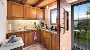 A kitchen with wooden cabinets, a sink, and a stove. - Rustico San Martin With Garden in Monti di Dritto (Cugnasco-Gerra)