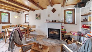 A cozy living room with a fireplace, wooden furniture, and a dining area with a table set for four. - Rustico San Martin With Garden in Monti di Dritto (Cugnasco-Gerra)