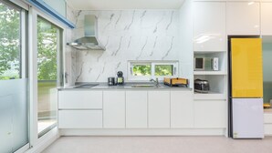A modern kitchen with white cabinets, a stainless steel range hood, a microwave, and a yellow refrigerator. - Gyeongsan Stage-ipple pet Pension (Gyeongsan)