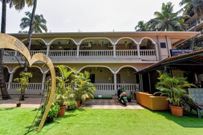 A resort with a two-story building, a covered outdoor seating area, and potted plants. - Rosa Bella Resort (Calangute)