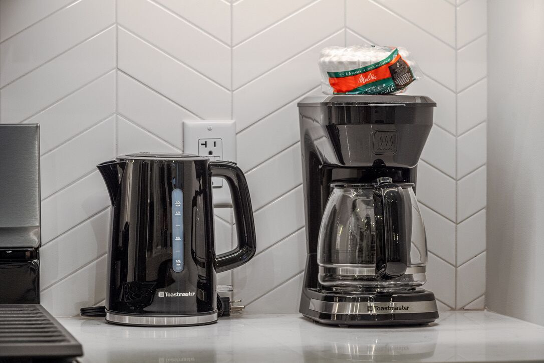 A kitchen with a toaster, a coffee maker, and a bag of coffee.