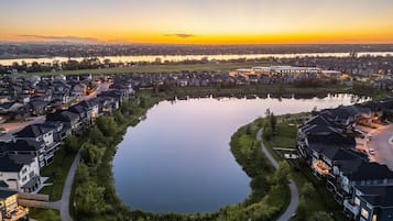 A residential area with houses, a lake, and a sunset.
