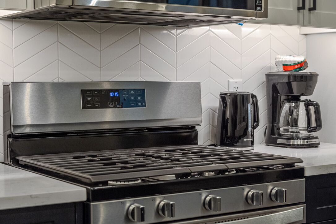 A kitchen with a stainless steel stove, a coffee maker, and a microwave.