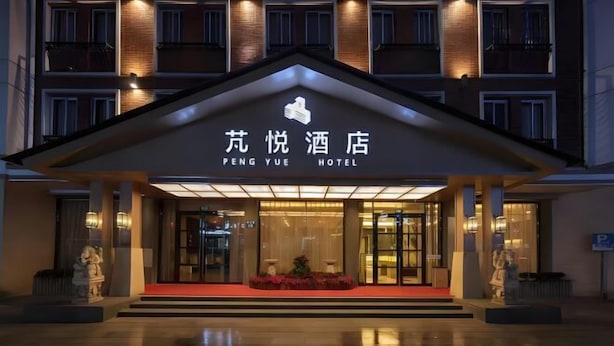 L’extérieur de l’hôtel Peng Yue se distingue par son entrée imposante, un tapis rouge et une statue de chaque côté de l’entrée.