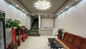 A reception area with a reception desk, a staircase, a bench, and potted plants. - Yijia Business Hotel (Guilin North Railway Station) (Guilin)
