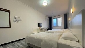 A hotel room with two beds, a TV, a mirror, and a window with curtains. - Yijia Business Hotel (Guilin North Railway Station) (Guilin)