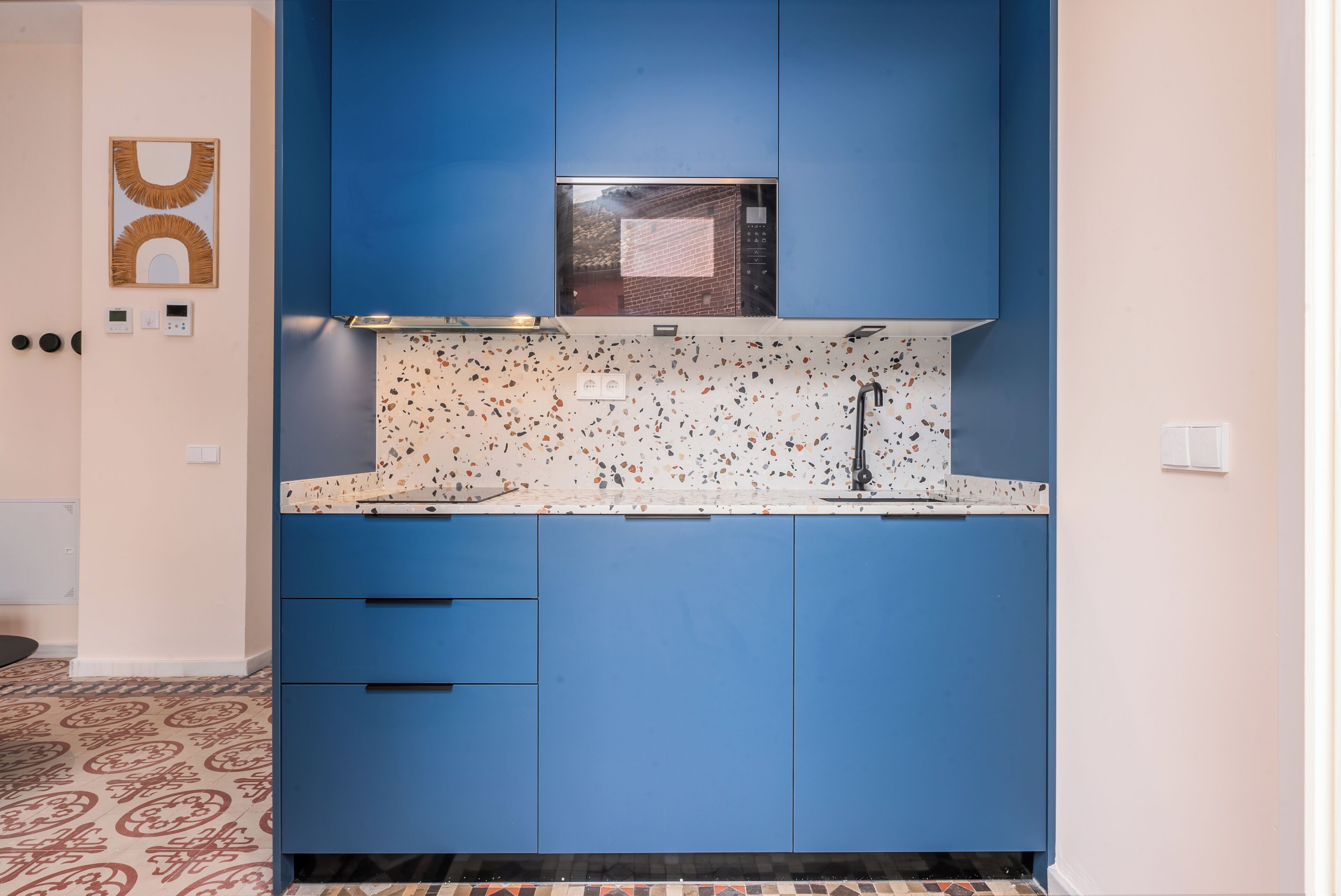 Una cocina con armarios azules, salpicadero moteado y microondas.