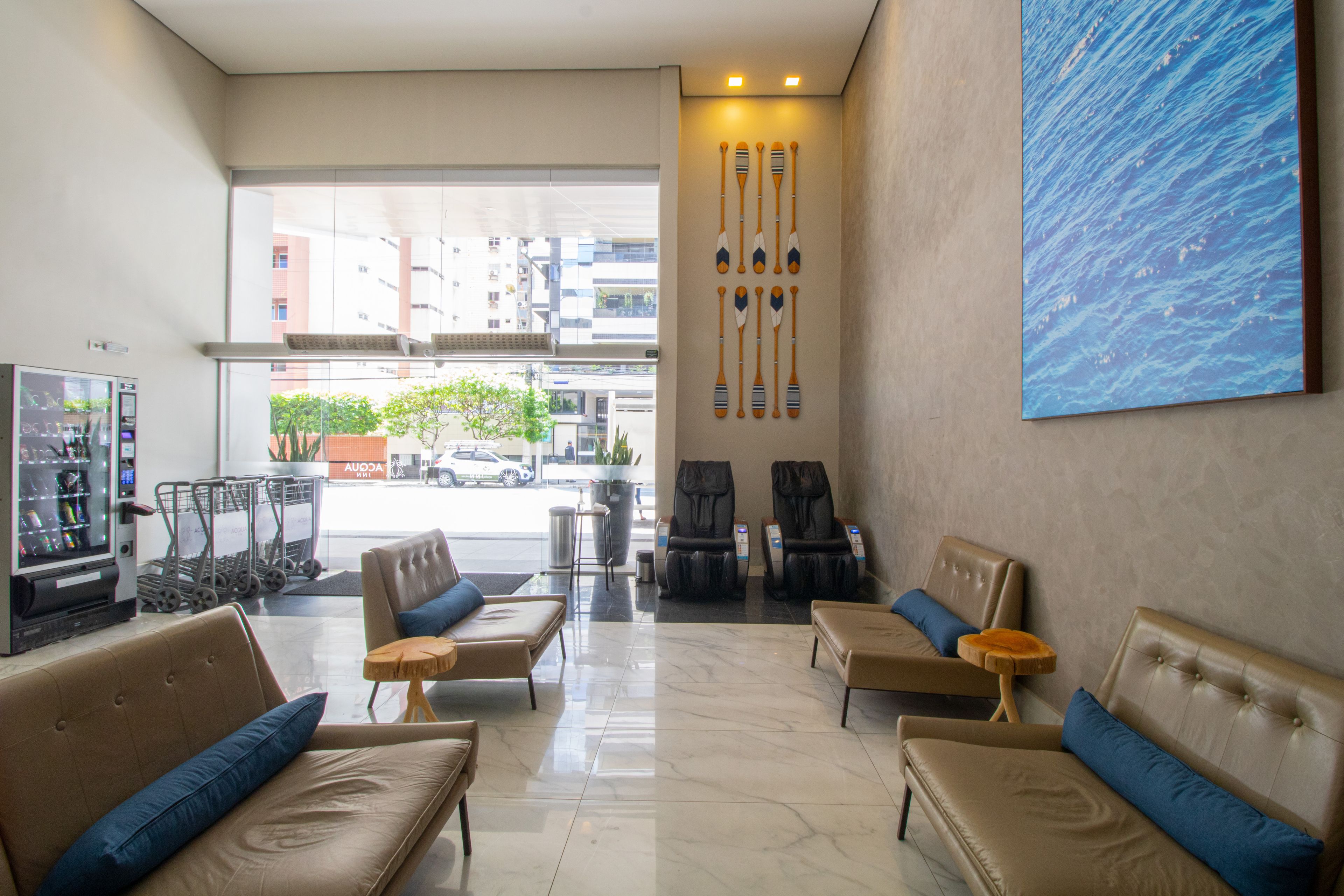 A hotel lobby with leather sofas, a vending machine, and a large window offering a view of the street.