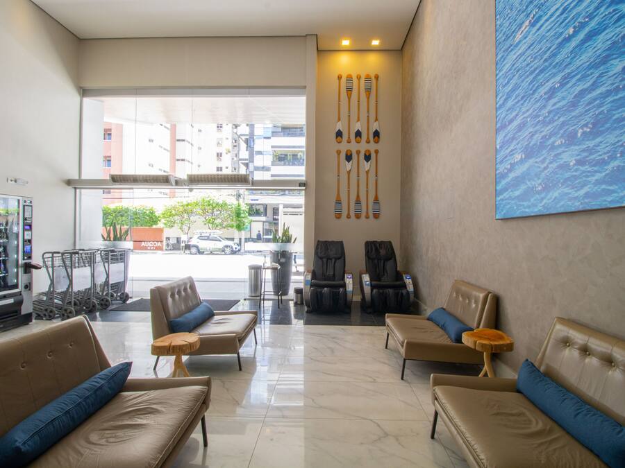 Hall d'hotel con divani in pelle, una macchina distributrice e un'ampia vetrata che dà su via.