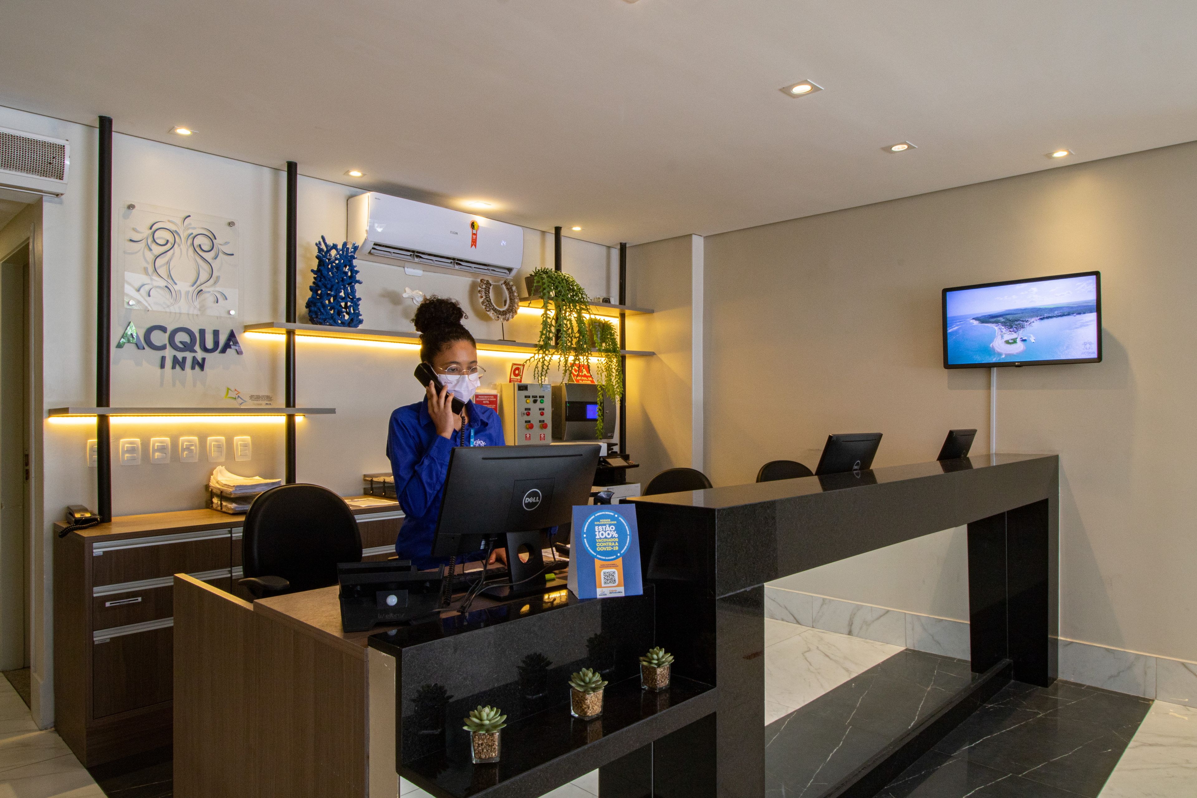 Mostrador de recepción de hotel con computadora, monitor y un cartel que indica un programa de fidelización.