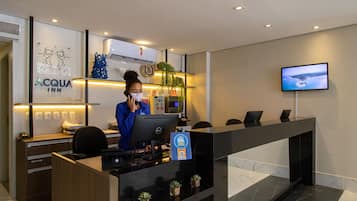 Mostrador de recepción de hotel con computadora, monitor y un cartel que indica un programa de fidelización.