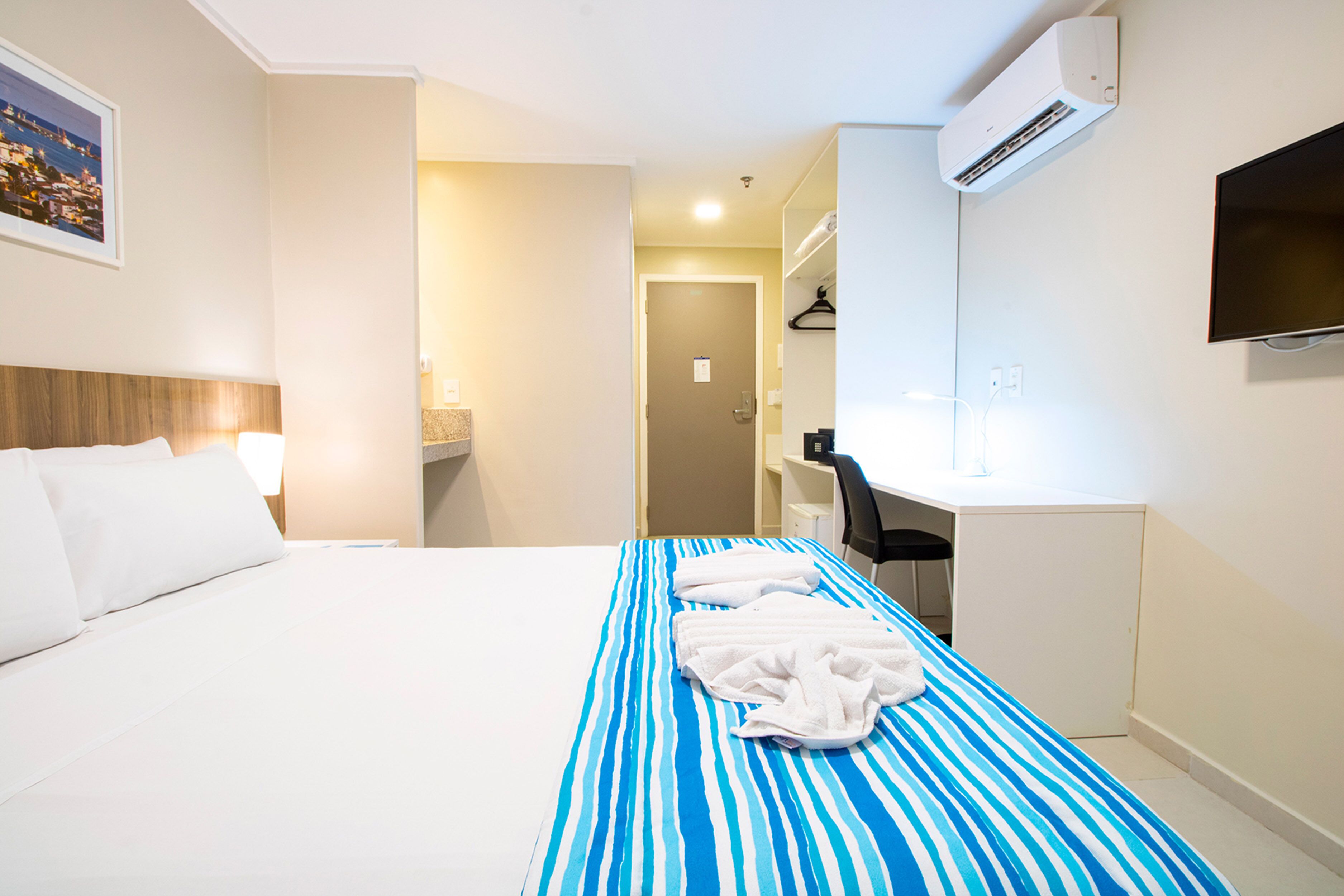 Una habitación de hotel con una cama, un escritorio y un televisor.