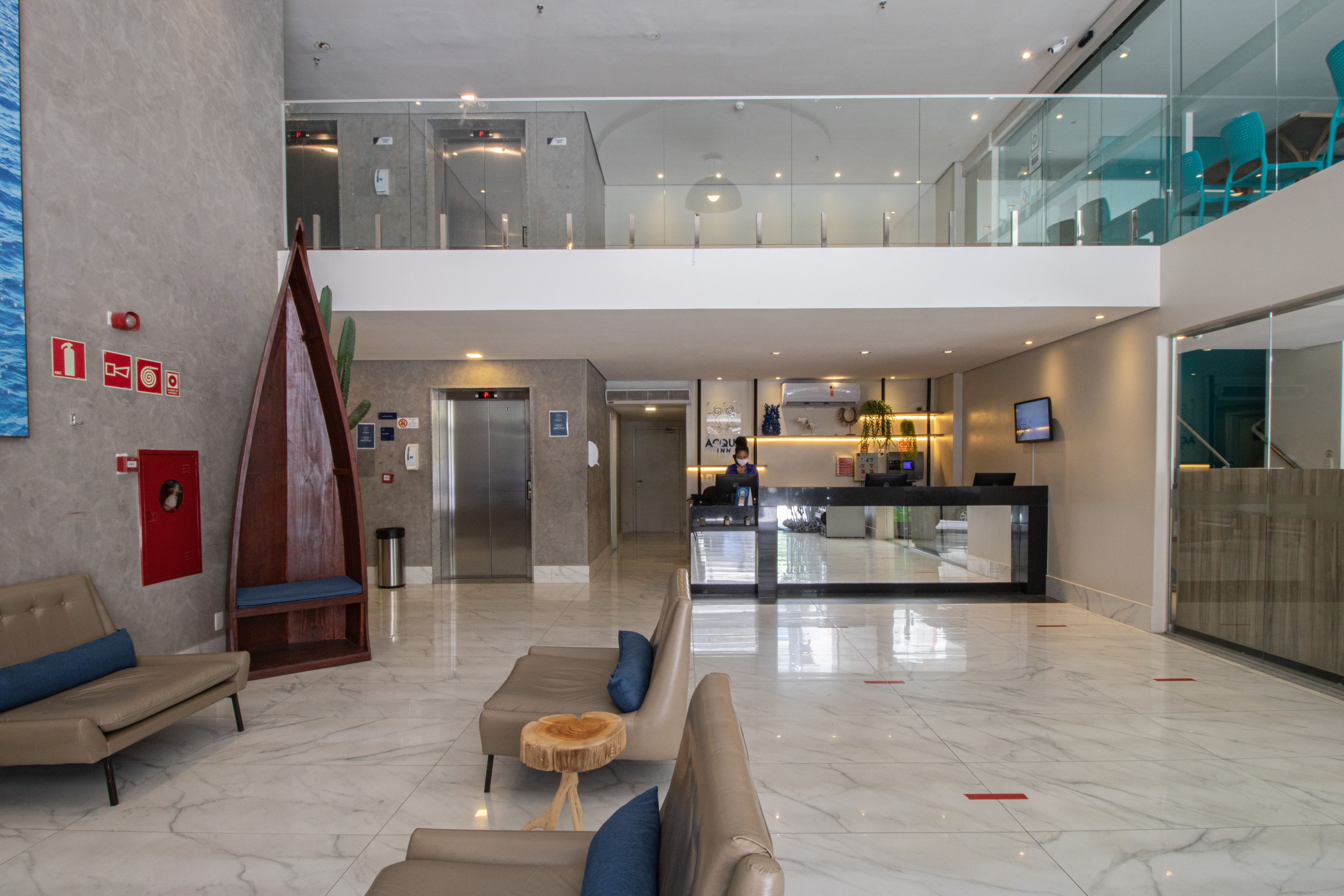 Un lobby moderno con una recepción, un área de estar y una escalera que sube a un nivel superior.