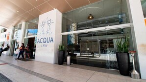 The exterior of the ACQUA INN, featuring a modern glass facade, a prominent logo, and potted plants. - Acqua Inn Maceio Ponta Verde (Maceió)