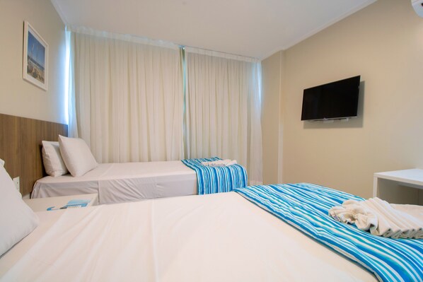 A hotel room with two beds, a TV, and a window with curtains. - Acqua Inn Maceio Ponta Verde (Maceió)