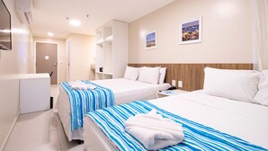 Hotellihuone, jossa on kaksi sänkyä, työpöytä, tuoli, vaatekaappi ja kylpyhuone.