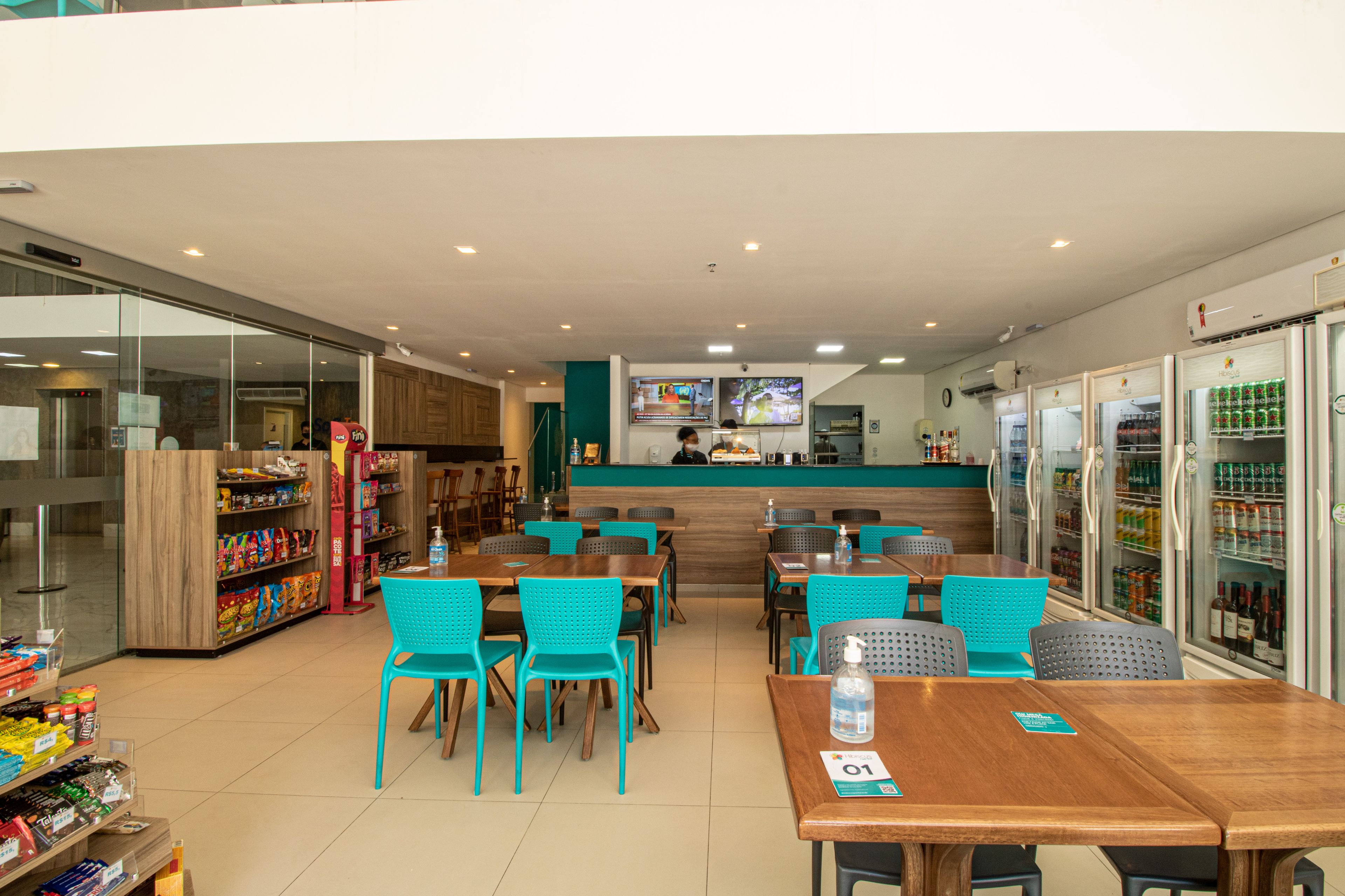Un restaurante con mesas, sillas, una barra y vitrinas refrigeradas.