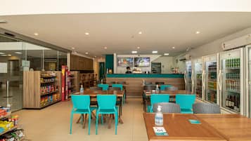 Un restaurante con mesas, sillas, una barra y vitrinas refrigeradas.