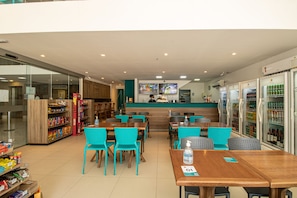 A restaurant with tables and chairs, a counter, and refrigerated display cases. - Acqua Inn Maceio Ponta Verde (Maceió)