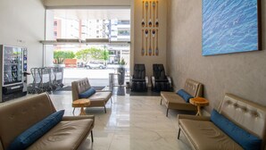 A hotel lobby with leather sofas, a vending machine, and a large window offering a view of the street. - Acqua Inn Maceio Ponta Verde (Maceió)