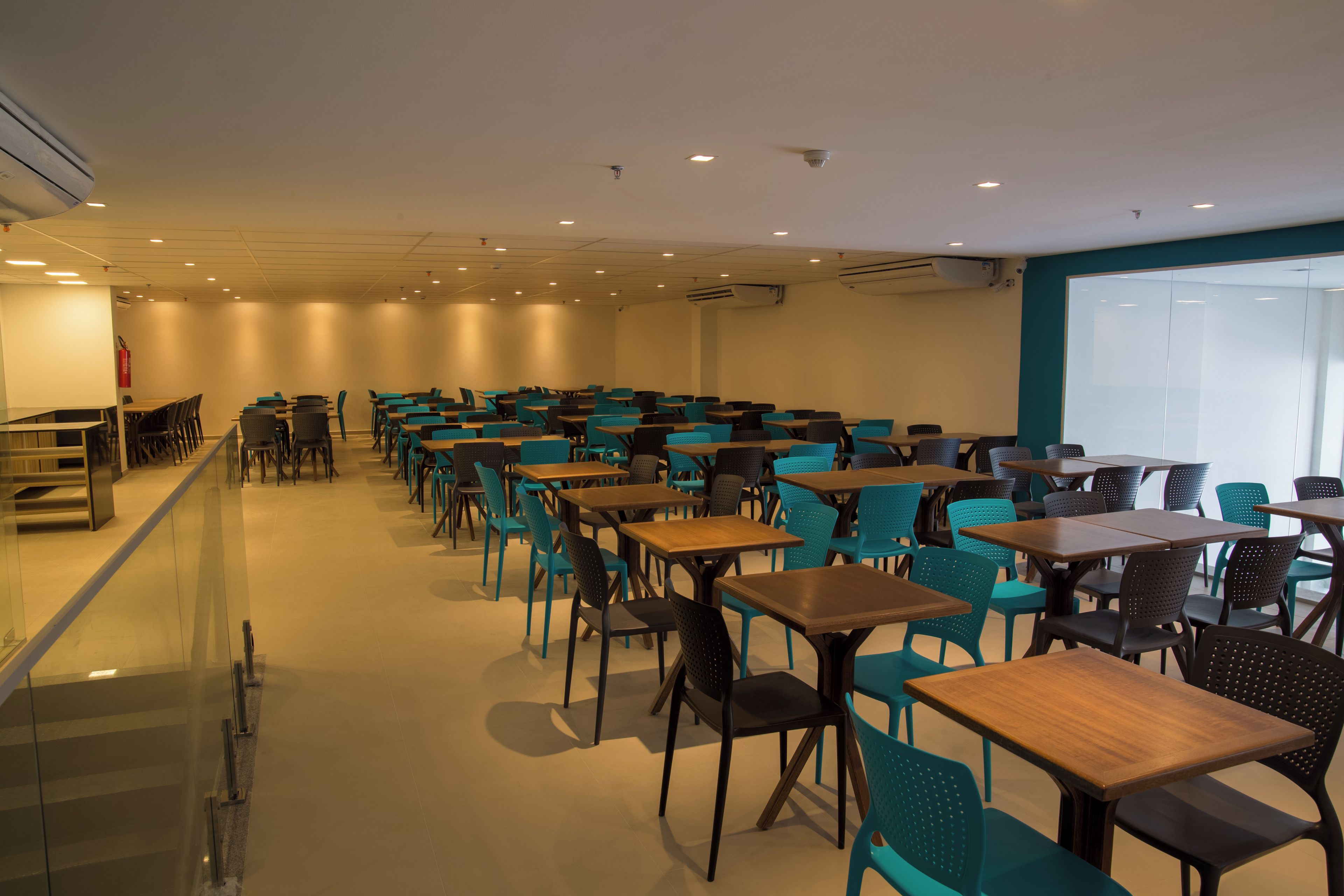 A conference room with rows of tables and chairs, a glass partition, and a whiteboard on the wall.