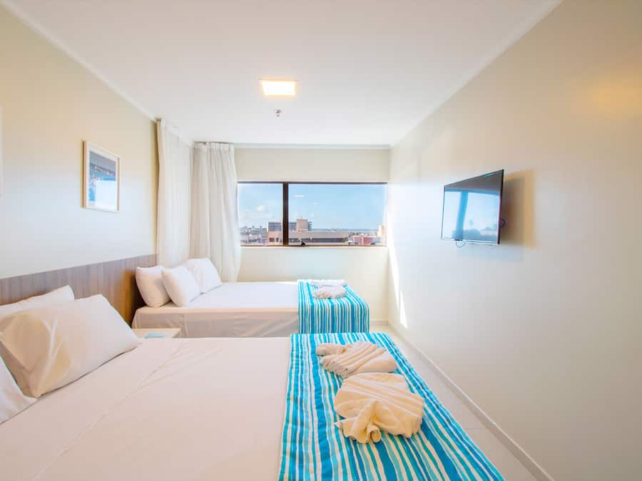 Een hotelkamer met twee bedden, een televisie en een raam met uitzicht over de stad.