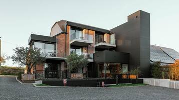 Una casa moderna de dos plantas con techo plano, ventanas grandes y un balcón.
