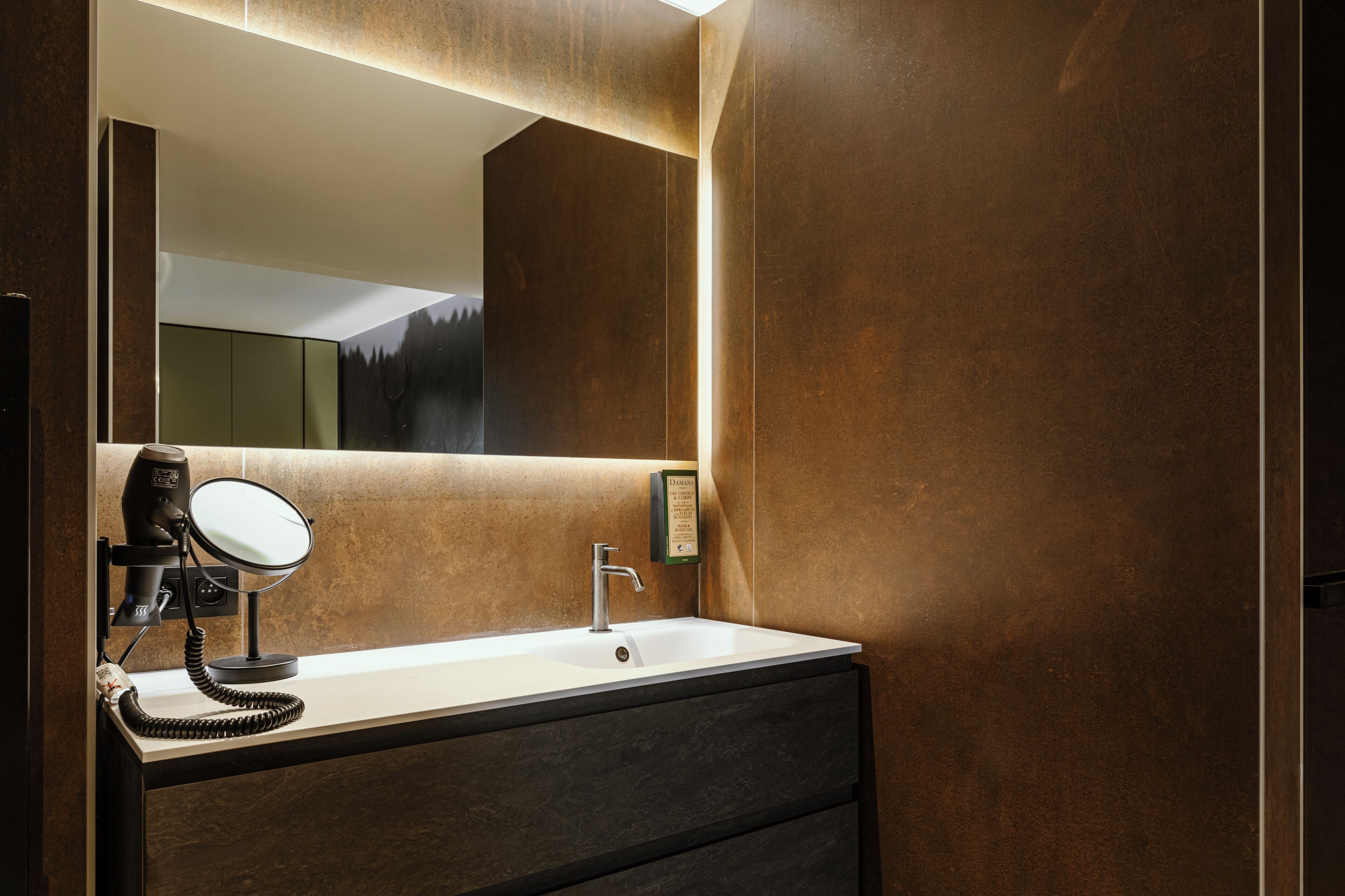 Une salle de bain moderne avec un grand miroir, un sèche-cheveux et un lavabo.