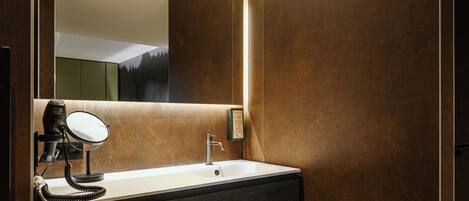 A modern bathroom with a large mirror, a hairdryer, and a sink.