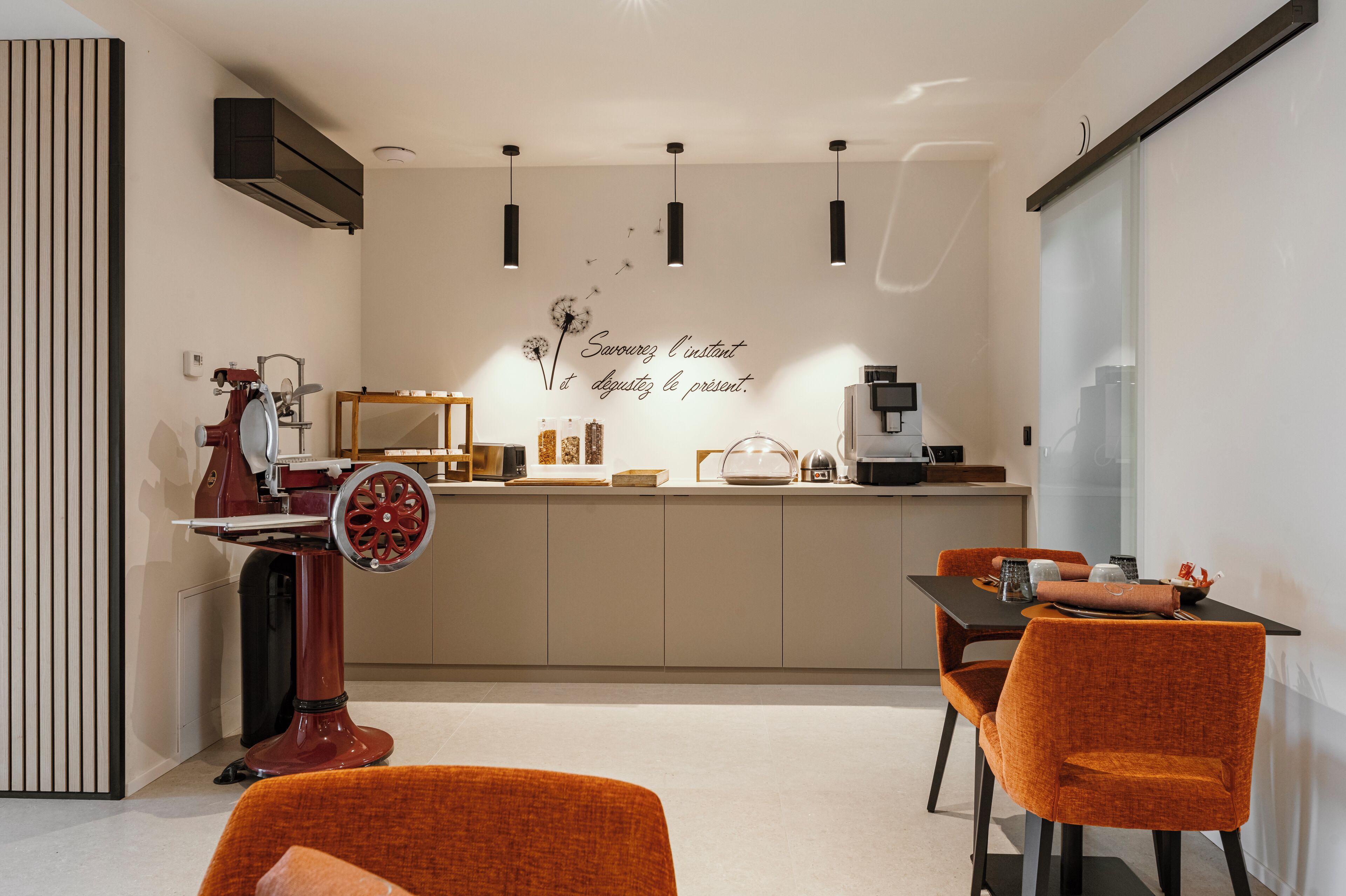 A modern kitchen with a central island, pendant lights, and a decorative wall with a French phrase.