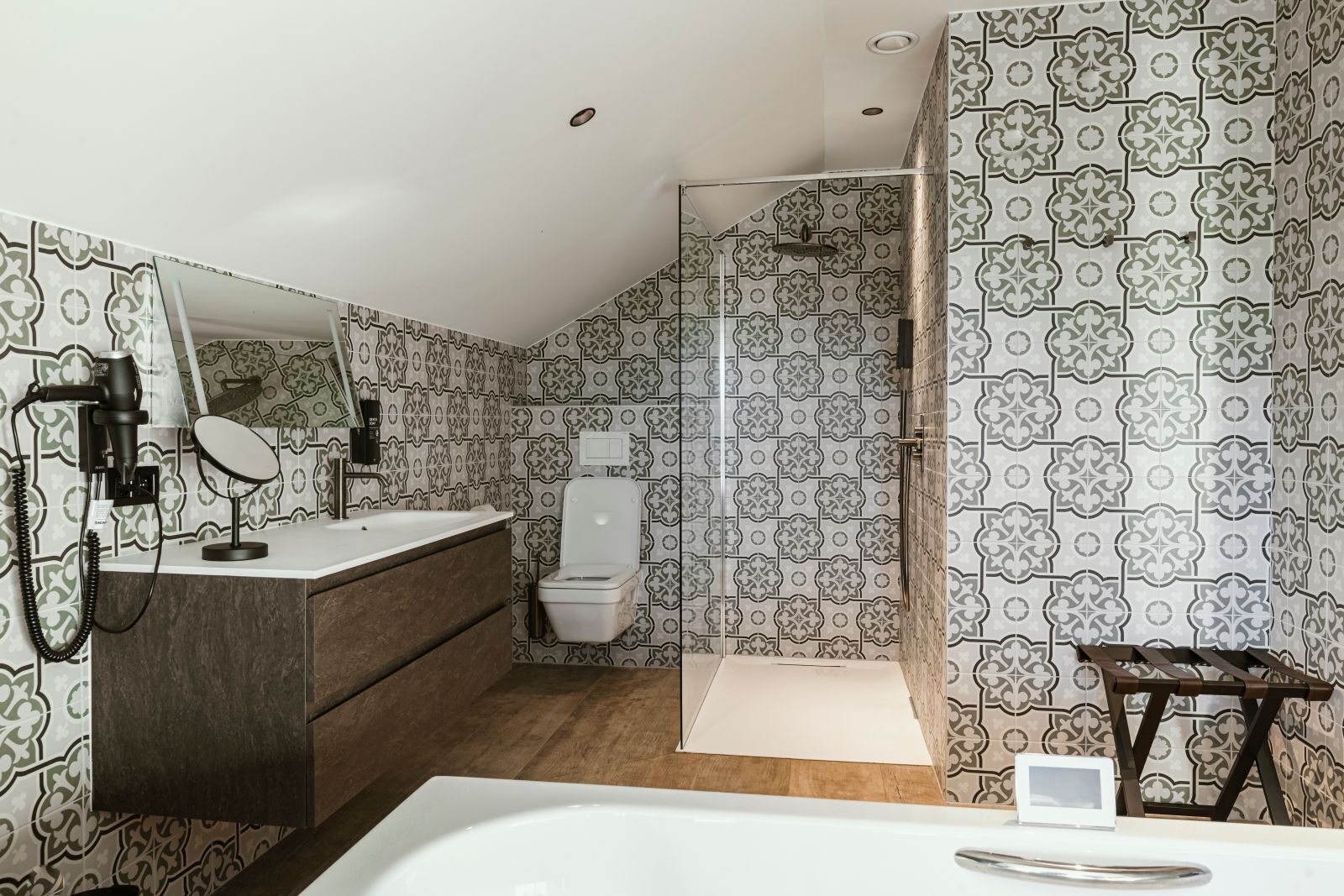 Un bagno con piastrelle decorate, un lavandino bianco, un water e uno spazio doccia.