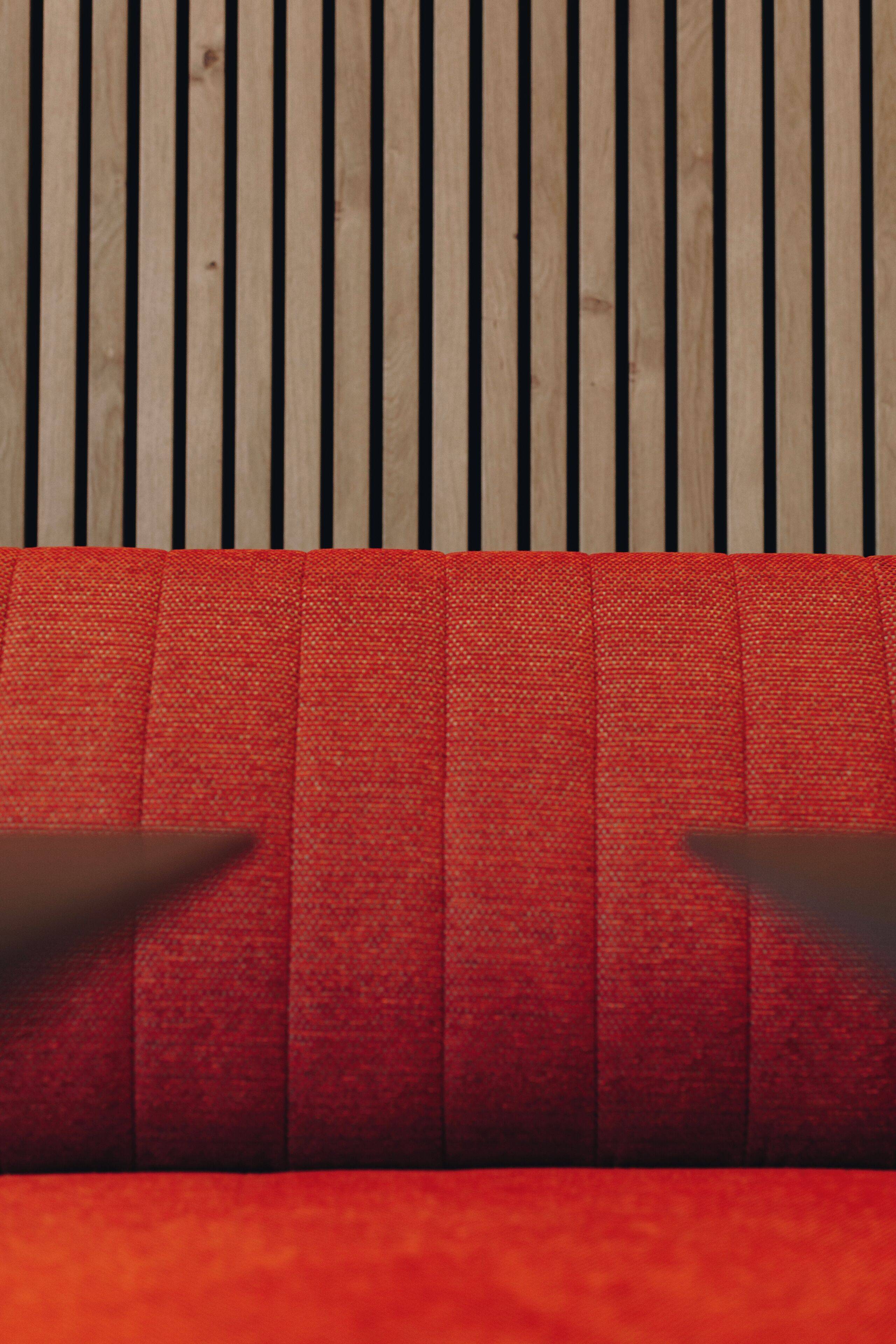 A close-up of a wooden floor with vertical planks and a red patterned carpet.