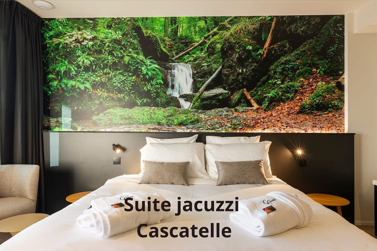A hotel room with a large bed, a headboard with a forest-themed mural, and a view of cascading water.