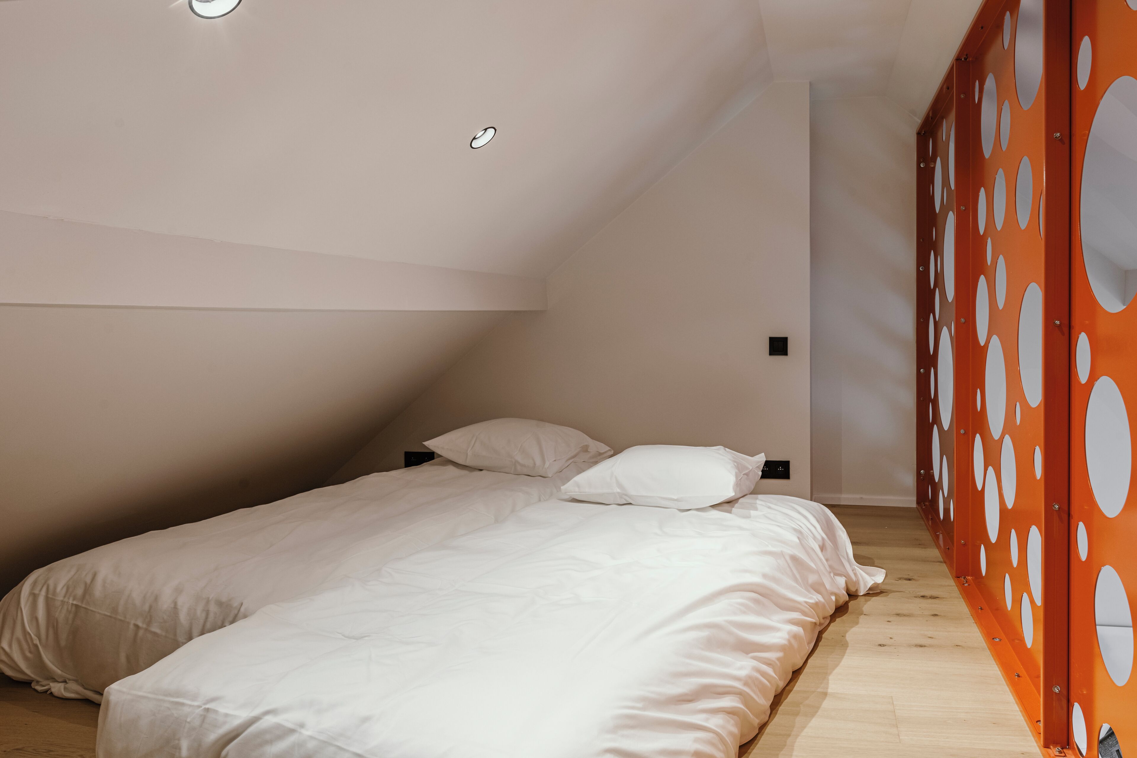 Ein Schlafzimmer mit zwei Betten, einer schrägen Decke und Holzboden.