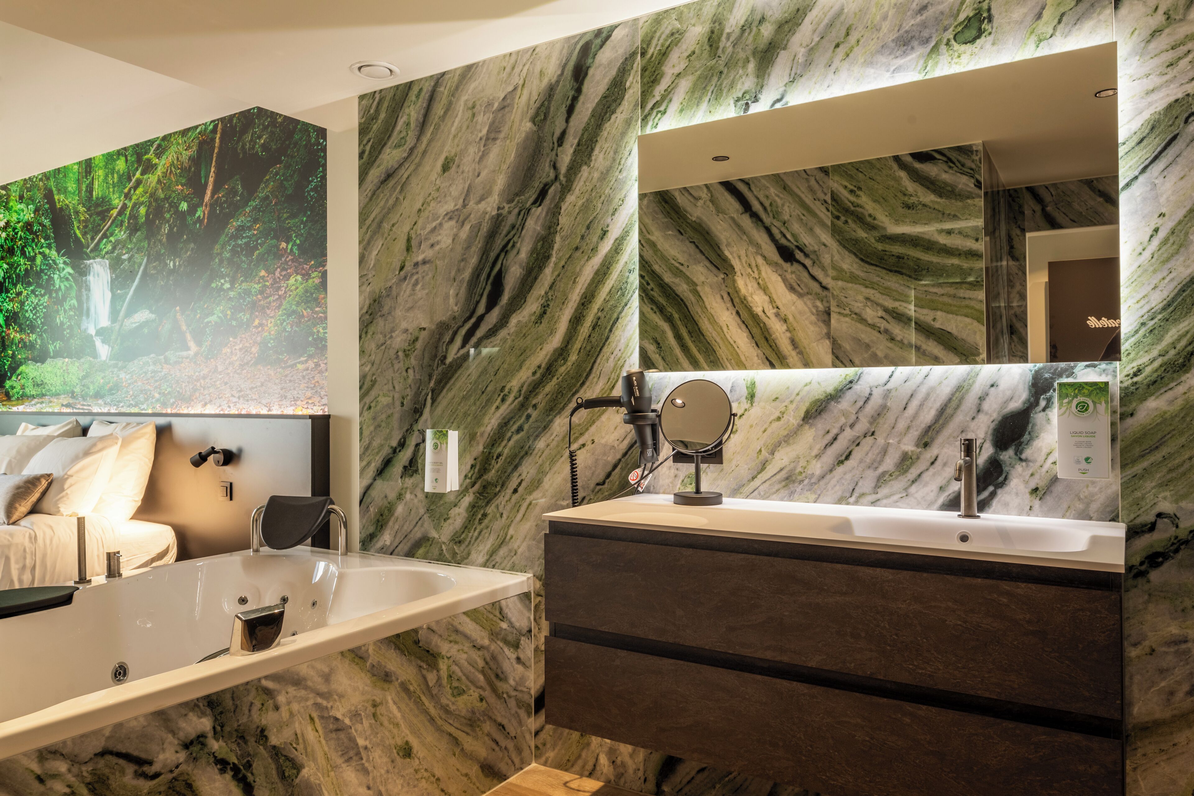 Une salle de bain moderne avec un grand miroir, une baignoire et un mur en marbre.