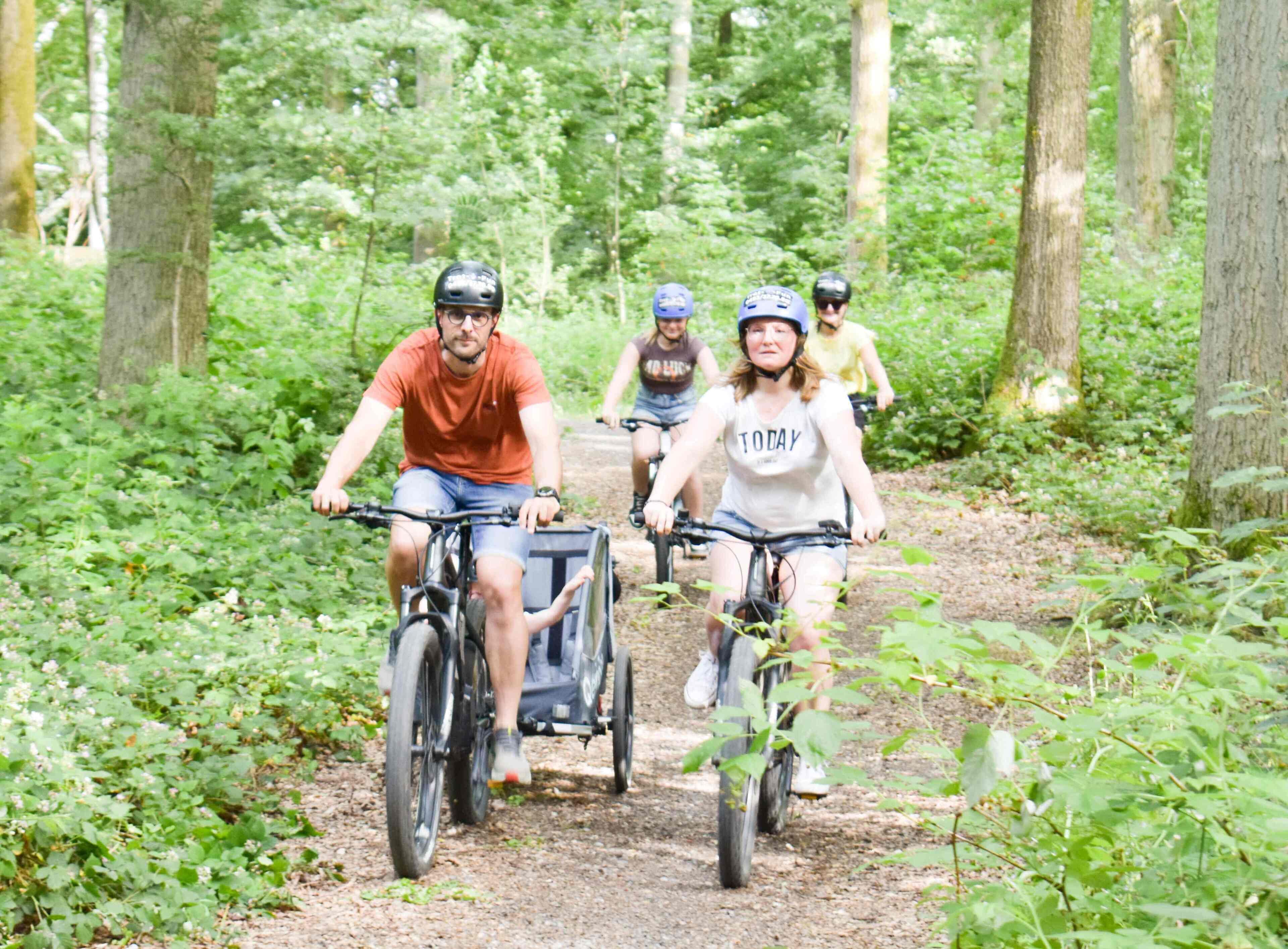 Een groep mensen fietst op een bospad.