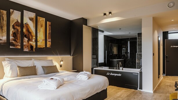 A modern hotel room with a large bed, a minibar, and artwork on the wall. - CC Nomie Hôtel Restaurant (Dinant)