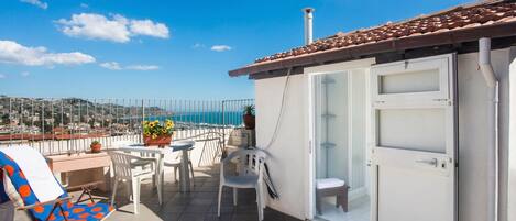 A balcony with a table, chairs, and a view of the sea.